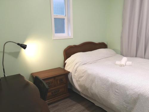 ein Schlafzimmer mit einem Bett und einem Tisch mit einer Lampe in der Unterkunft Countryroad Cozy 2Bedrooms suite2 in Nanaimo