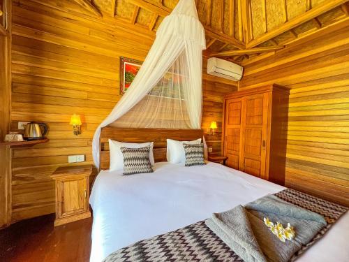 ein Schlafzimmer mit einem Bett in einer Holzhütte in der Unterkunft Skywatch cottage in Klungkung