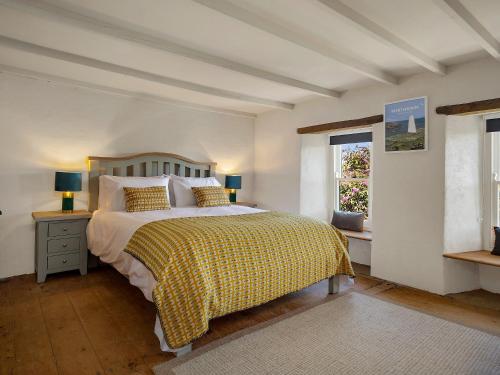 a bedroom with a bed with a yellow blanket and a window at Alma Cottage in Solva