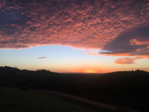 a sunset over a field with the sun setting at Lush rural retreat in Korumburra
