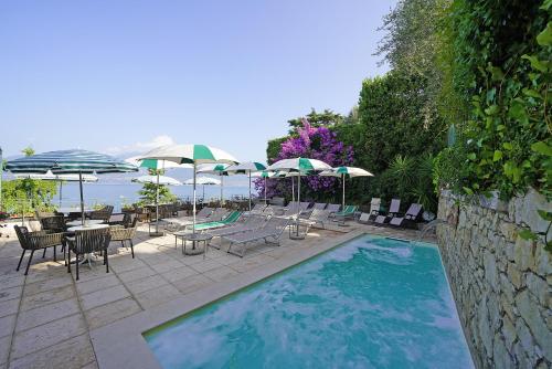 una piscina con sillas, mesas y sombrillas en Hotel Villa Carlotta, en Torri del Benaco