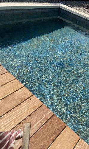 une piscine d'eau avec une terrasse en bois dans l'établissement Gite Couleur Terre à 10MN de Gordes, à Croagnes
