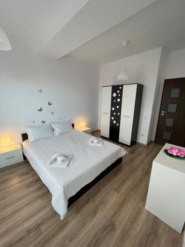 een slaapkamer met een groot wit bed en houten vloeren bij WOW Park Drumul Taberei apartment in Boekarest