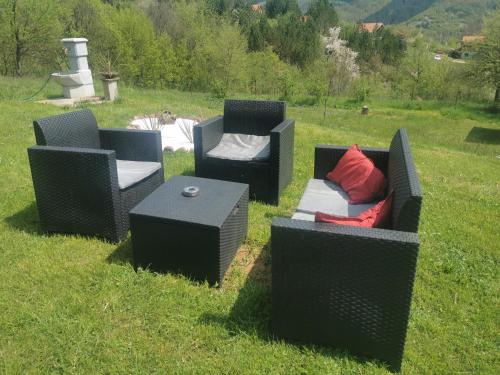 three wicker chairs and a table in a field at Vila Jotic, Zavojsko jezero in Pirot