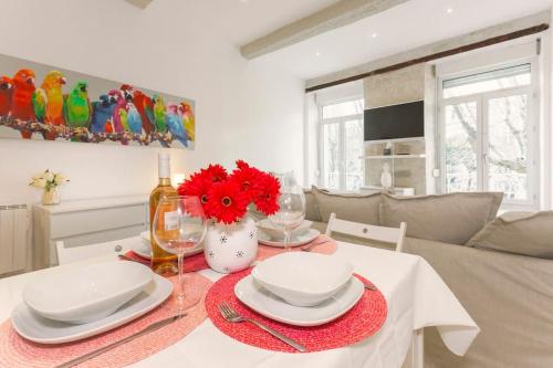 - une table à manger avec des assiettes et des fleurs rouges dans l'établissement La Loge de l'Horloge - 1 min PALAIS DES PAPES - AC CLIM - WIFI - HYPERCENTRE - vue sur le carrousel, à Avignon