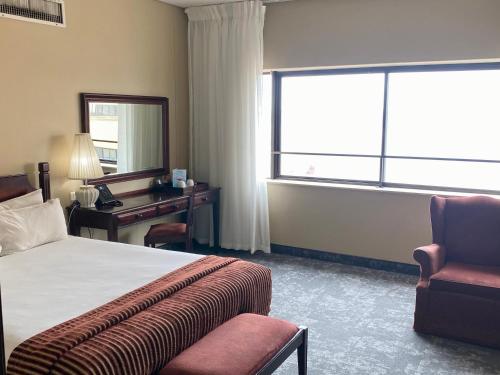 a hotel room with a bed and a desk and a chair at The Royal Hotel by Coastlands Hotels & Resorts in Durban