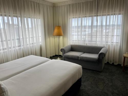 a hotel room with a bed and a chair and window at The Royal Hotel by Coastlands Hotels & Resorts in Durban