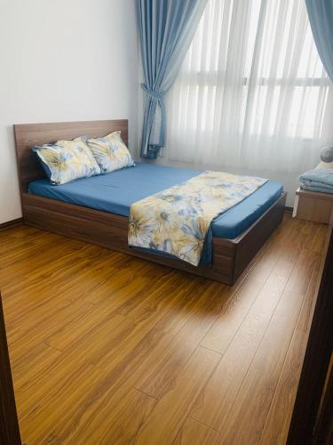 Bett in einem Schlafzimmer mit Holzboden in der Unterkunft Quy nhon Color- Căn hộ du lịch Quy Nhơn 3 in Quy Nhon