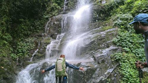 Ein Mann steht vor einem Wasserfall. in der Unterkunft OYO Home Narayan Homestay & Adventures in Pelling