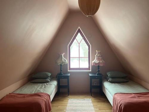 a attic room with two beds and a window at Längtan Marielund in Uppsala