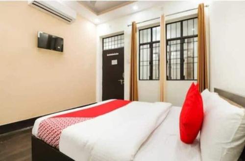 a bedroom with a bed with red pillows and a door at OYO Gupta Guest House in Morādābād