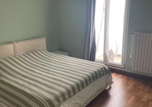 um quarto com uma cama com uma colcha listrada e uma janela em La Magnolia Apartaments IV em Desenzano del Garda
