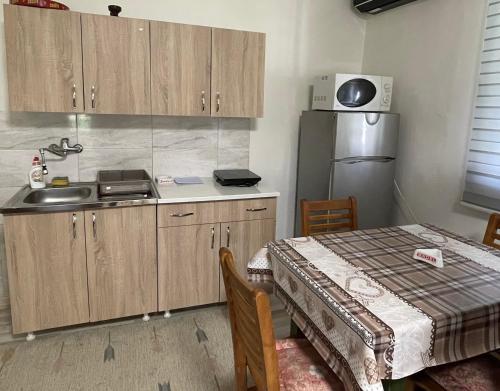 a kitchen with a table and a sink and a refrigerator at Vikendica Cerović in Kraljevo