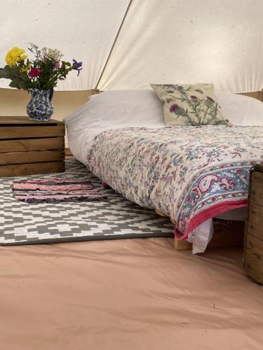 a bed with a pillow and a vase of flowers at Willow glamping in Norwich