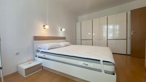 a white bedroom with a bed and a cabinet at Bratanov Yassen Holiday Vilage in Sunny Beach