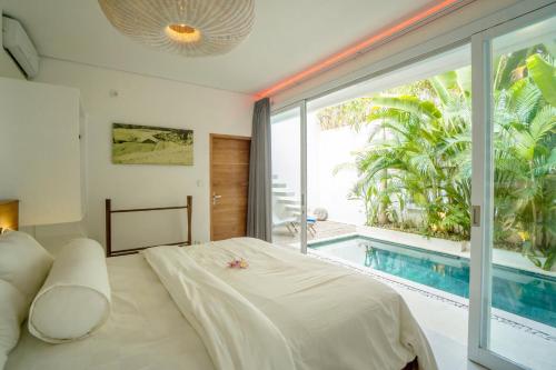 een slaapkamer met een bed en een groot raam met een zwembad bij Musik Villa Canggu in Canggu