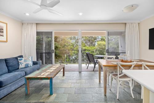 a living room with a blue couch and a table at 1 36 Alderly Tce Little Cove in Noosa Heads