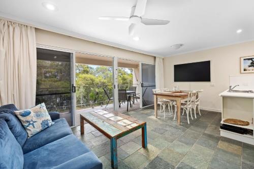 a living room with a blue couch and a table at 1 36 Alderly Tce Little Cove in Noosa Heads