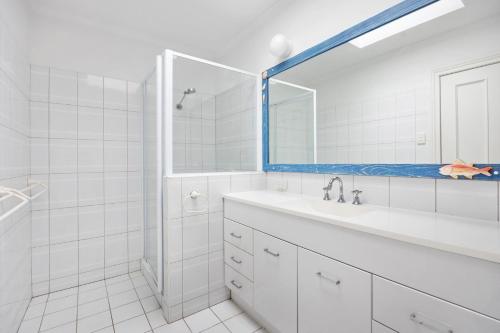 a white bathroom with a sink and a mirror at 1 36 Alderly Tce Little Cove in Noosa Heads