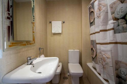 ein Badezimmer mit einem Waschbecken, einem WC und einem Spiegel in der Unterkunft A view of the beach duplex in Málaga