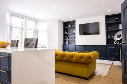 a living room with a yellow couch and a tv at Designer Cardiff Apartments in Cardiff