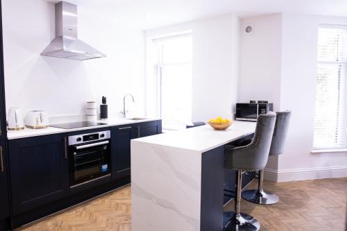 a kitchen with black cabinets and white counter tops at Designer Cardiff Apartments in Cardiff