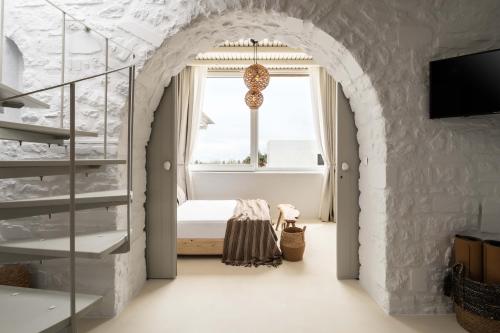 a bedroom with an archway with a bed and a window at Cavos Paros Boho Chic sea-view apartment in Aliki in Aliki