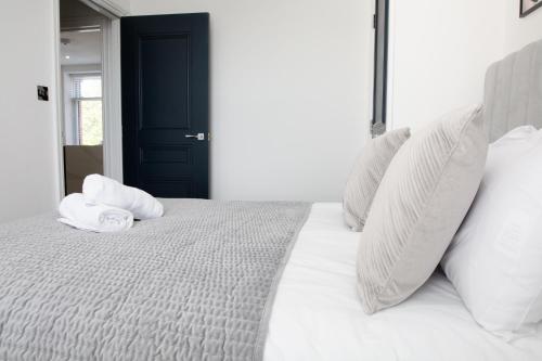 a white bed with two pillows on top of it at Designer Cardiff Apartments in Cardiff