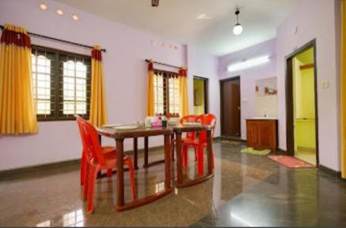 a dining room with a table and red chairs at MUNNAR FALCUNS INN HOMESTAY in Munnar