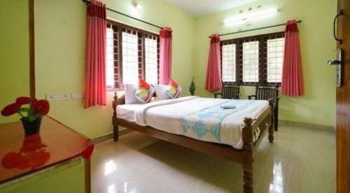 1 dormitorio con 1 cama grande y cortinas rojas en MUNNAR FALCUNS INN HOMESTAY en Munnar