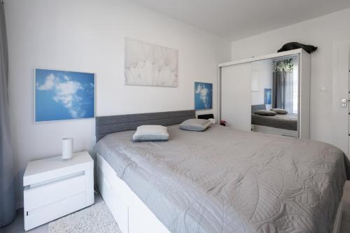 een witte slaapkamer met een groot bed en een spiegel bij Red Bridge Apartament in Dziwnów
