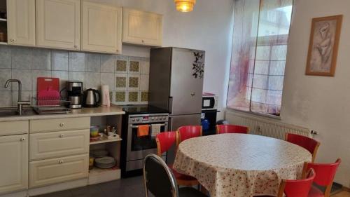 uma cozinha com uma mesa, cadeiras vermelhas e um frigorífico em Apartment Karin em Dresden