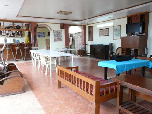 sala de estar con mesas y bancos y cocina en Casa de las Palmeras, en Pansol