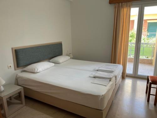 a bedroom with a large white bed and a window at Neapolis Apartments in Palaiochóra