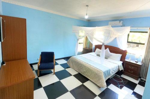 a bedroom with a bed and a chair in a room at Main Stream Beach Villa in Senga