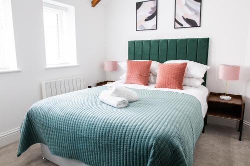 a bedroom with a large bed with a green headboard at Designer Cardiff Apartments in Cardiff