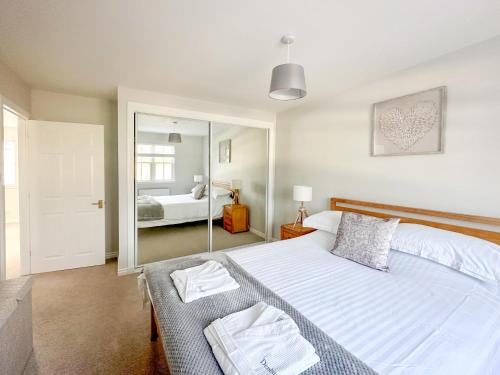 1 dormitorio con 1 cama blanca grande y espejo en Denburn Cottage, en Colinsburgh