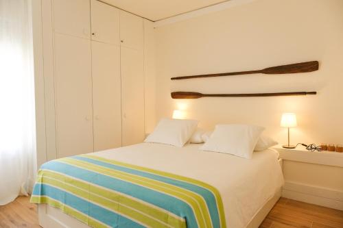 a bedroom with a bed with a colorful striped blanket at Troia Beach and Nature - Apartment in Troia
