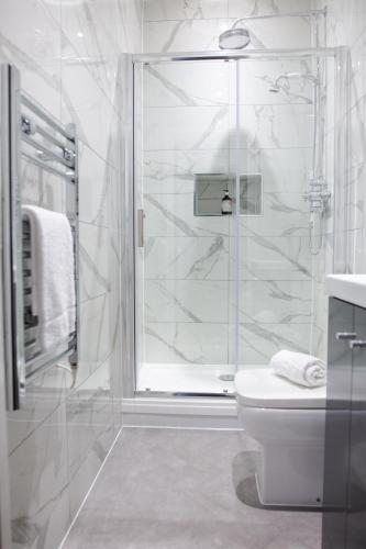 a white bathroom with a shower and a toilet at Designer Cardiff Apartments in Cardiff