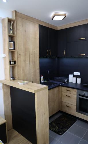 a kitchen with black and wooden cabinets and a counter at Danica apartman in Gornji Milanovac