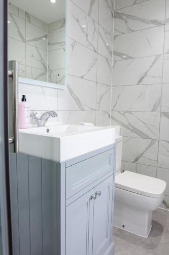 a white bathroom with a sink and a toilet at Designer Cardiff Apartments in Cardiff