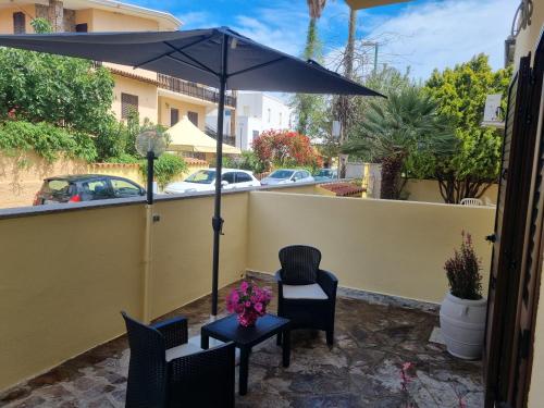 a patio with an umbrella and chairs and a table at Il Giglio del Mare in La Caletta