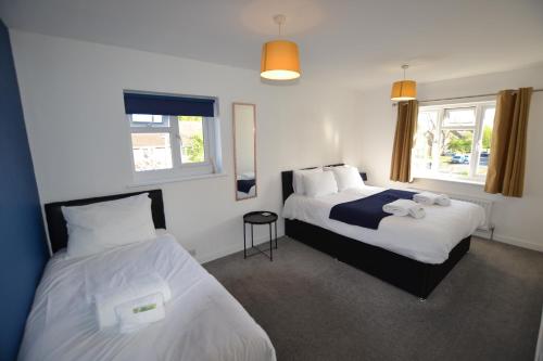 a hotel room with two beds and two windows at Wisteria 2 bed House - STAYSEEKERS in Salisbury
