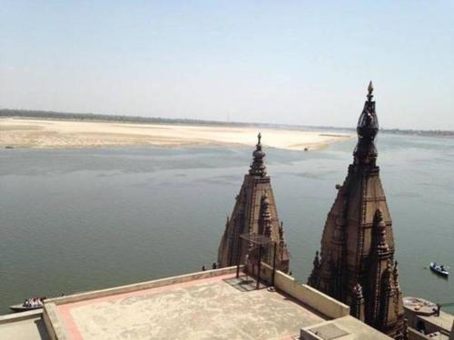 a building with two towers next to the water at Bhadra Kali Guest House in Varanasi