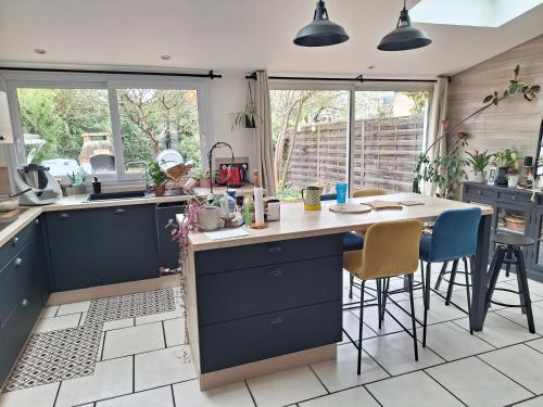 une cuisine avec des placards bleus et une table avec des chaises dans l'établissement Chambre chez l'habitant, au Mans