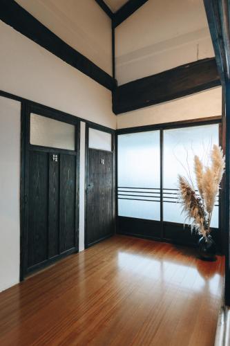 a room with black doors and a vase with feathers at 一棟貸しの古民家 燕と土と in Tokimata