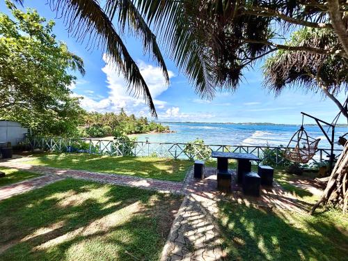 a picnic table on the beach with a view of the ocean at Kenno's Korner in Weligama
