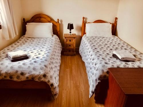 a bedroom with two beds and a table with a lamp at Inverken House in Inshes