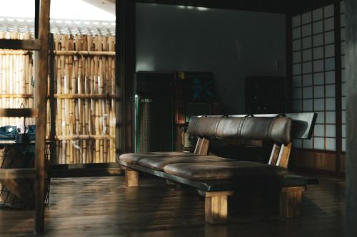 a leather bench sitting in a room with a window at 一棟貸しの古民家 燕と土と in Tokimata