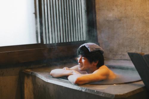 a young boy sitting in a bath tub at 一棟貸しの古民家 燕と土と in Tokimata